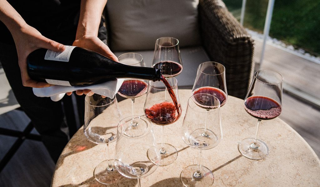 red wine being poured into glasses at a restaurant in italy